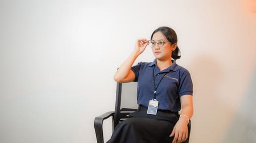 Female Outdesk Staff member sitting on an office chair, looking relaxed with her hand on her glasses looking intrigued